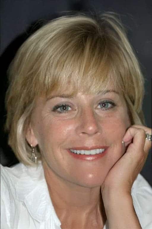 Here's an alt tag for the image: Smiling blonde woman with bangs.