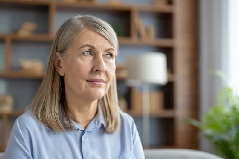 Dental Implants Homer Glen 1 Thoughtful mature woman in a blue shirt.