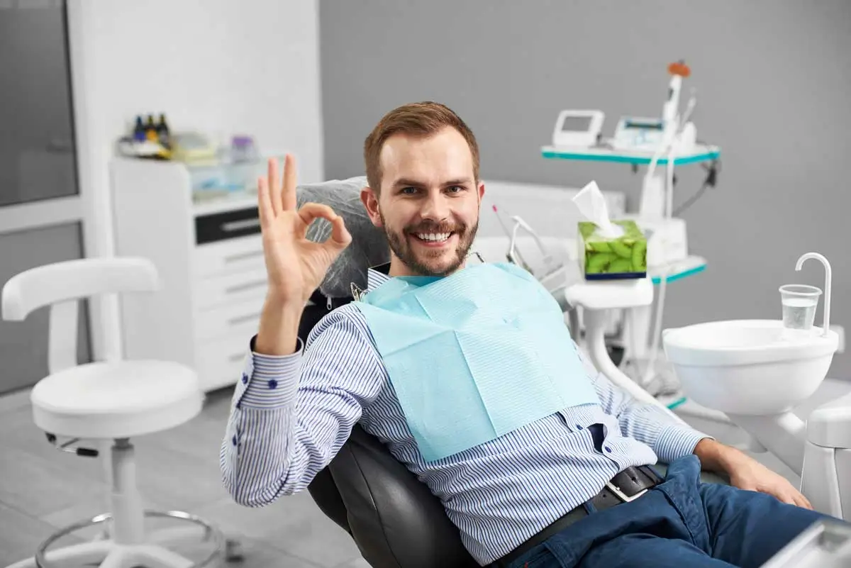 Happy patient showing okay sign at dentist.