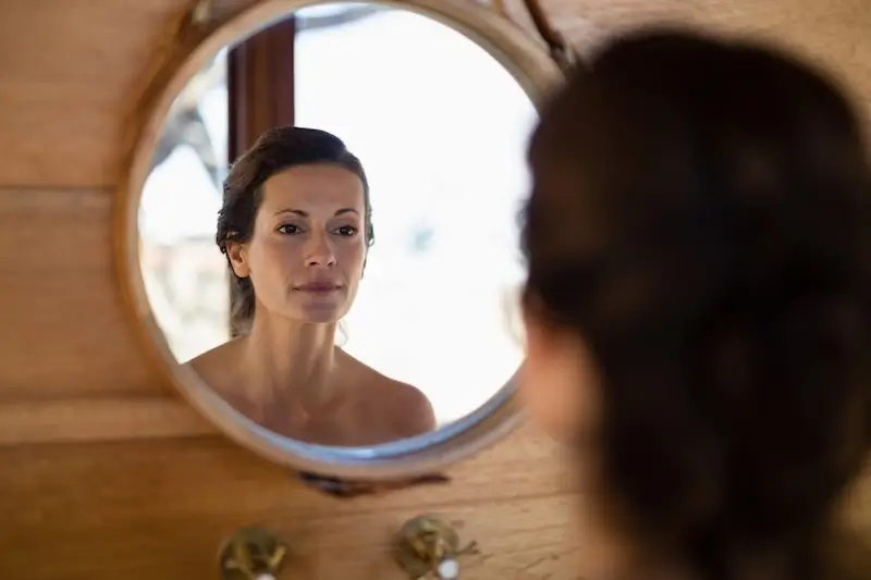 Woman looking at herself in mirror.